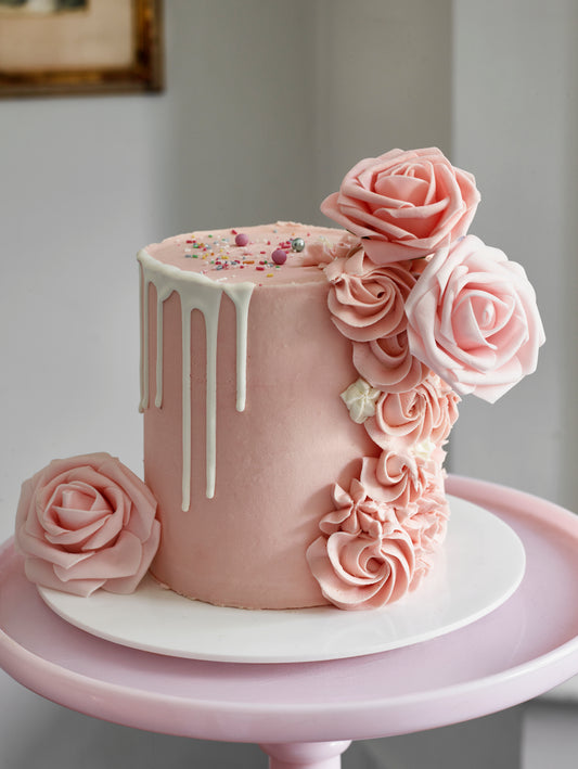 Cake decorated with buttercream roses, silk roses and a chocolate drip