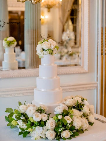 white 5 tiered wedding cake with fresh flowers on top and around the base