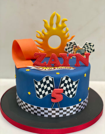 Cake with checkered flags and racing car elements and a large flame.