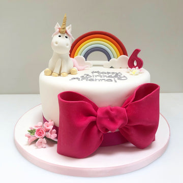 Single tier rainbow and unicorn cake with large pink bow