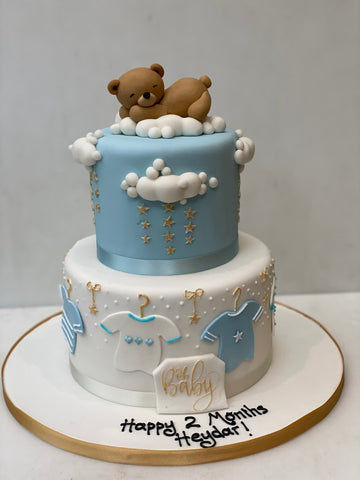 Babyshower or christening Cake decorated with a sleeping teddy bear, baby clothes, clouds and stars