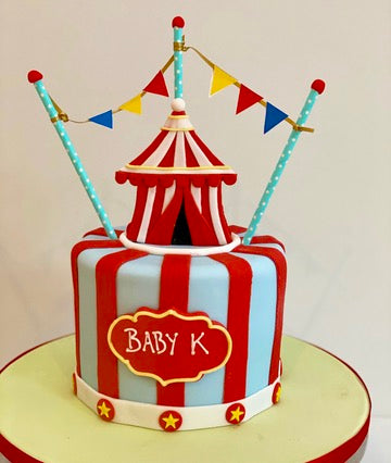 Circus-themed baby shower cake with striped design and 'Baby K' text