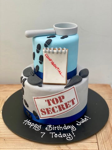 Spy themed birthday cake with spy themed decoration and a top secret sign