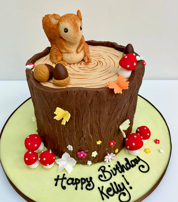 Cake decorated to look like a log with squirrel and toadstools on top