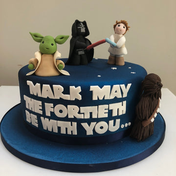 birthday cake with star wars decorations including yoda, darth vadar, luke skywalker and chewbacker
