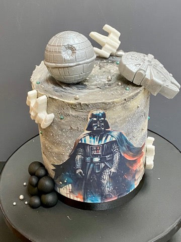 Star Wars-themed buttercream cake with Death Star, Darth Vader figure, and Millennium Falcon.
