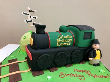 Cake Shaped like a steam train with a fat train master in front