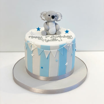 Birthday cake with stripes on the sides and a koala on top