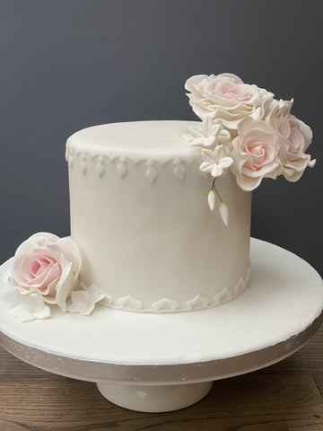 Simple and elegant christening cake decorated with sugar roses and blossom flowers