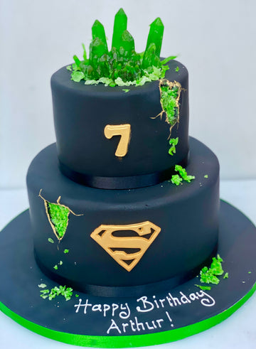 two tier black birthday cake with spiderman log and green kryptonite
