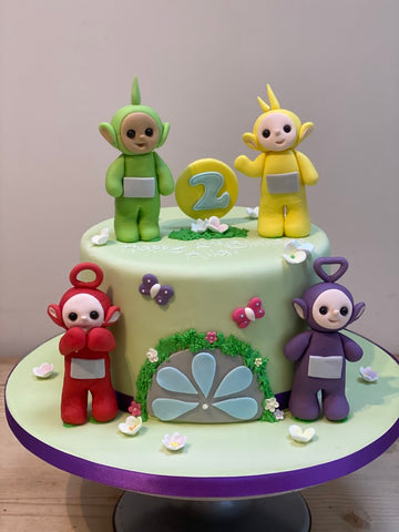 Green birthday cake with tellytubby icing sugar figures to decorate