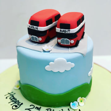 Two red double-decker buses on a cake with 'Happy 2nd Birthday' text