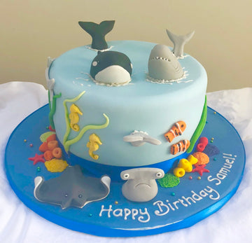 birthday cake decorated with sugar killer whale, sharks, and other sealife creatures