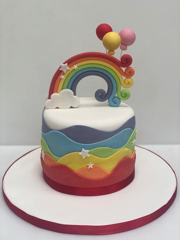 Birthday cake with wavy rainbow on the sides and curly rainbow on top