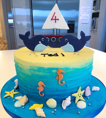 Buttercream birthday cake decorated with whales and a boat