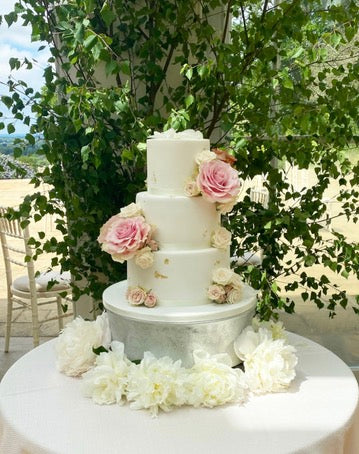 White three tiered wedding cake with large fresh flowers