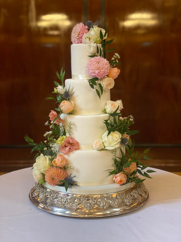 white 4 tier fondant wedding cake decorated with dahlias, roses and other flowers