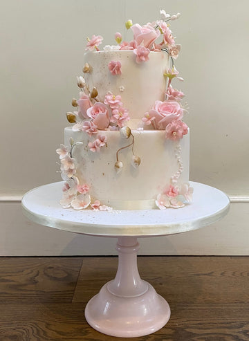 2 tier white cake with pink roses and pink blossoms cascading down the cake