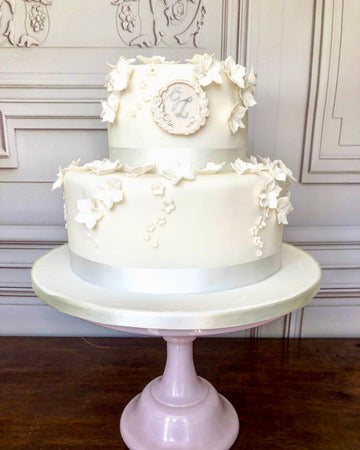 two tiered wedding cake with hydrangea blossoms and a plaque showing the couple's initials, delivered in london