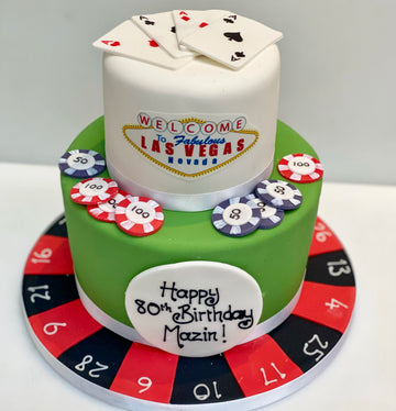 Cake decorated with Las Vegas theme, including cards, chips, and roulette wheel, with 'Welcome to Fabulous Las Vegas' sign.