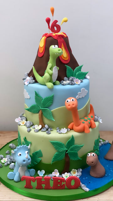 3 tier birthday cake with volcano on top and dinosaur figures