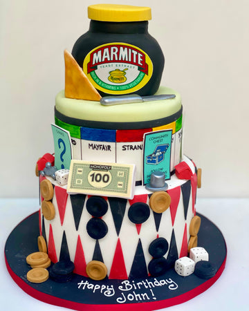 Three-tier birthday cake with Marmite jar, Monopoly elements, and drafts