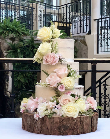 3 tier semi naked wedding cake with a swathe of pastel roses delivered in london