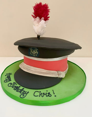 Cake designed like a military hat with red and white plume on a green base