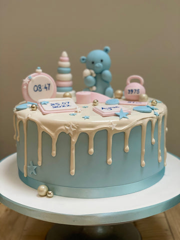 blue drip cake to celebrate a baby's arrival with teddy and other baby toys on the cake