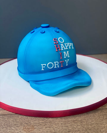 Blue cap-shaped cake with 'SO HAPPY I'M FORTY' text 