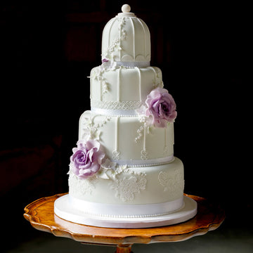 wedding cake designed to look like a bird cage with purple roses and intricate piping