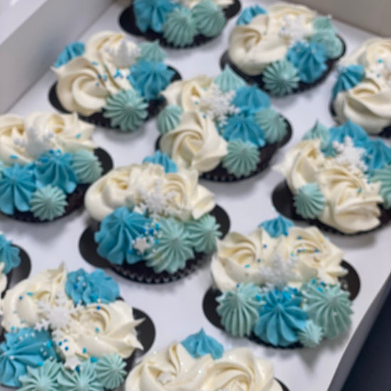 Assorted cupcakes with blue and white frosting on a tray.