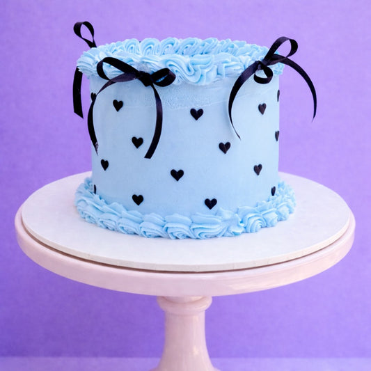 Pale blue birthday cake with black hearts and ribbon bows delivered in london