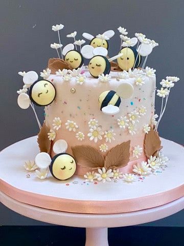 Kids birthday cake covered with sugar bees and flowers and daisies