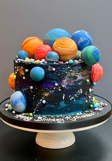 buttercream birthday cake in space theme with large colourful planets on top