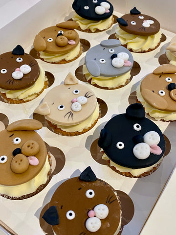 Cupcakes decorated with animal at and dog faces on a white tray
