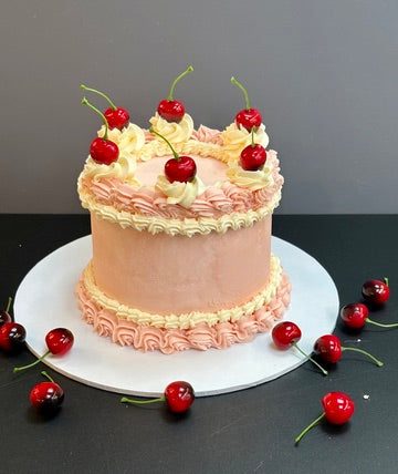 Pink buttercream cake decorated with piping and cherries ready to order in london