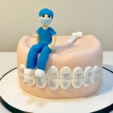 Cake decorated to look like teeth with a dentist sat on top