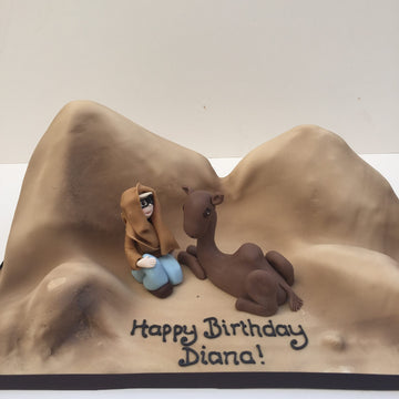 Desert scene cake with a woman and a camel on it