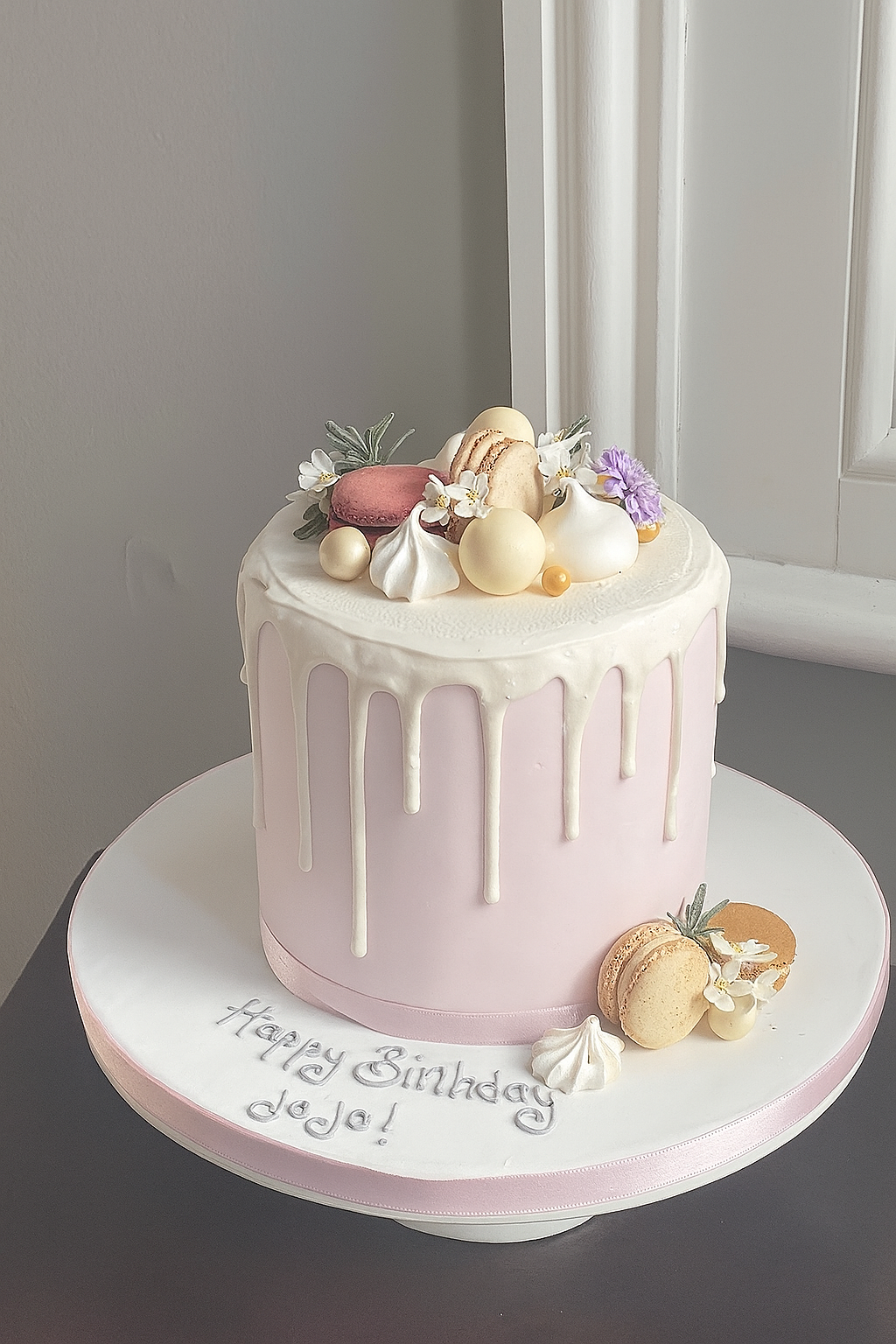 Pink drip cake with macarons, meringue kisses and chocolates to decorate