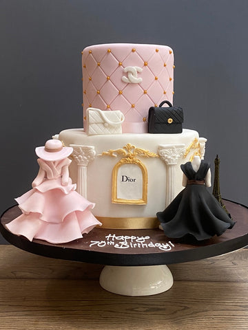 Decorative cake with fashion-themed elements like Chanel, Dior and beautiful dresses made from sugar