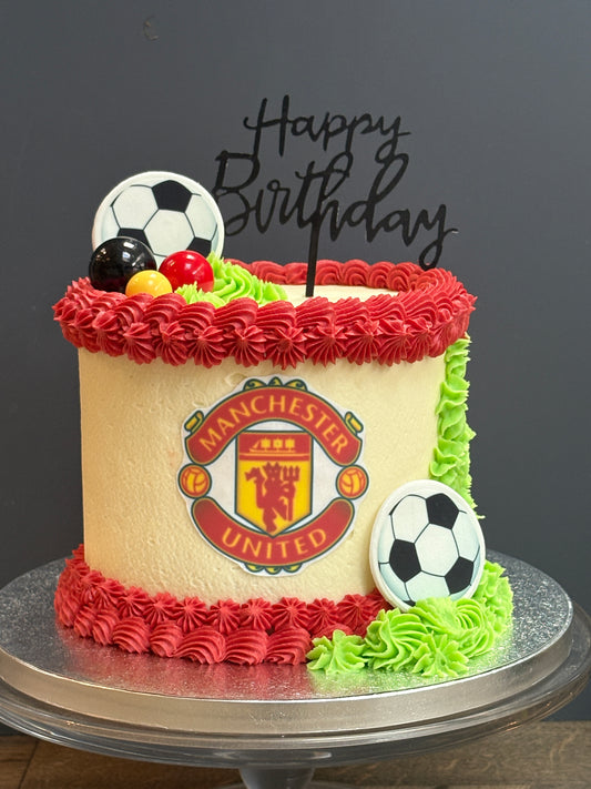 Birthday cake with Manchester United logo and soccer ball decorations on a black background for london delivery