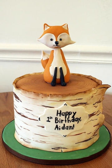 Cake decorated to look like a log with a sugar fox on top