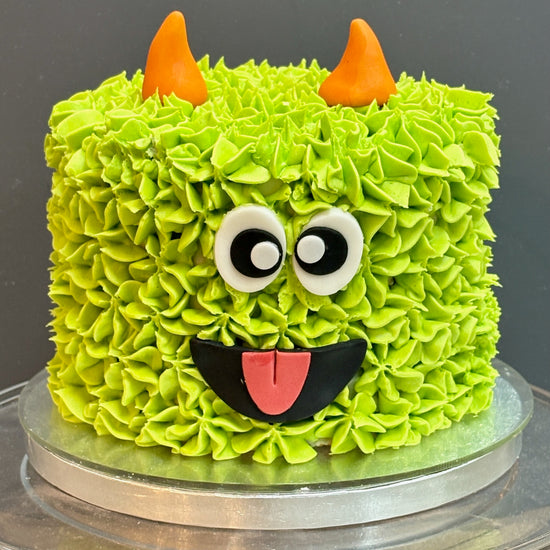 halloween cake styled to look like a green monster wtih horns and goggly eyes.  Perfect halloween cake for a halloween party