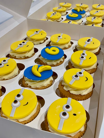 Cupcakes decorated to resemble Minions from the Despicable Me franchise, arranged in a box.