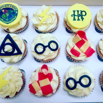 Cupcakes decorated with Harry Potter-themed designs on a white tray.