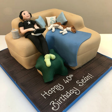 Sofa Shaped cake with a man and his dog lounging on it