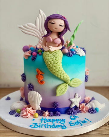 birthday cake with a mermaid on top and lots of shell and sea decorations. Birthday cakes delivered in london