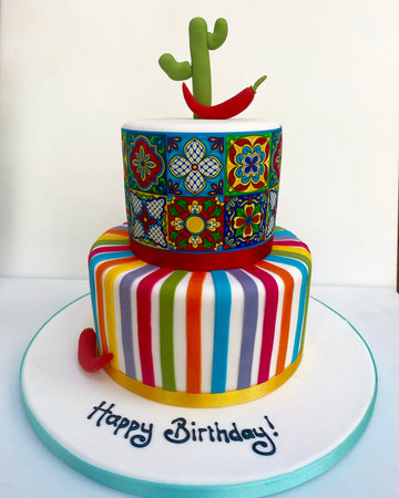 Colorful two-tier birthday cake with a cactus and chili pepper on top, featuring the text 'Happy Birthday!'.