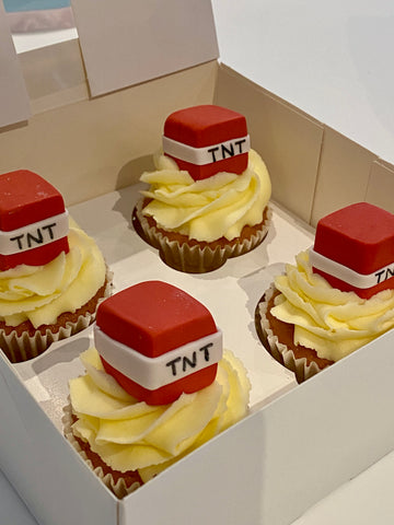 Cupcakes with TNT-themed toppers in a box